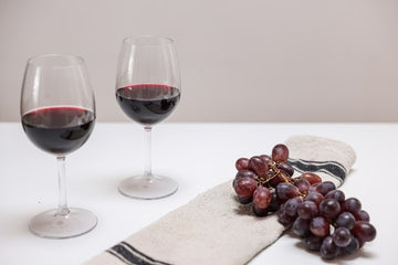 Two glasses of red wine beside red grapes
